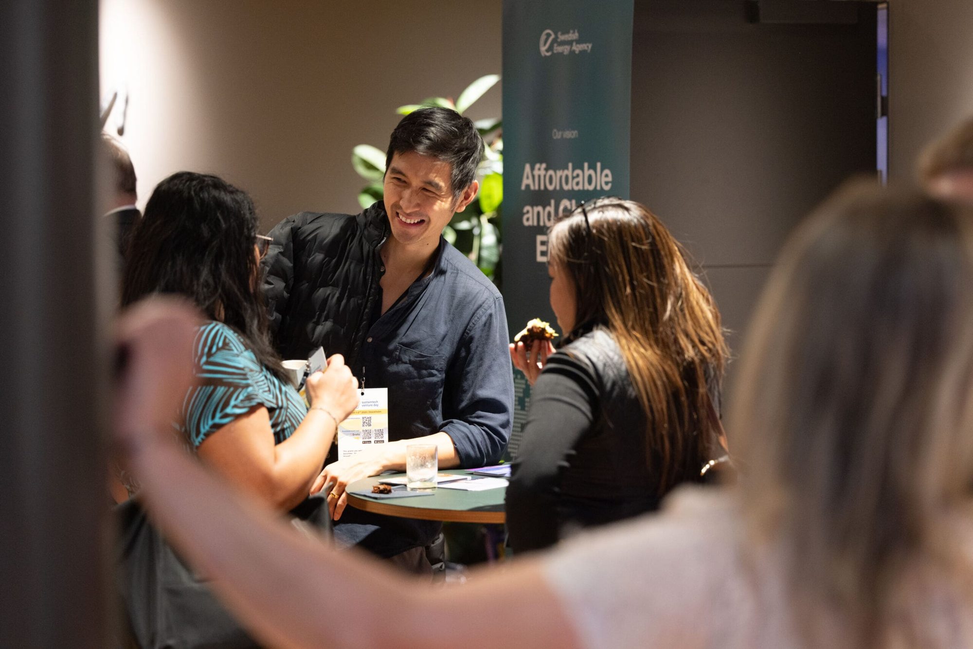 Three delegates talk around a standing table during the event mingle
